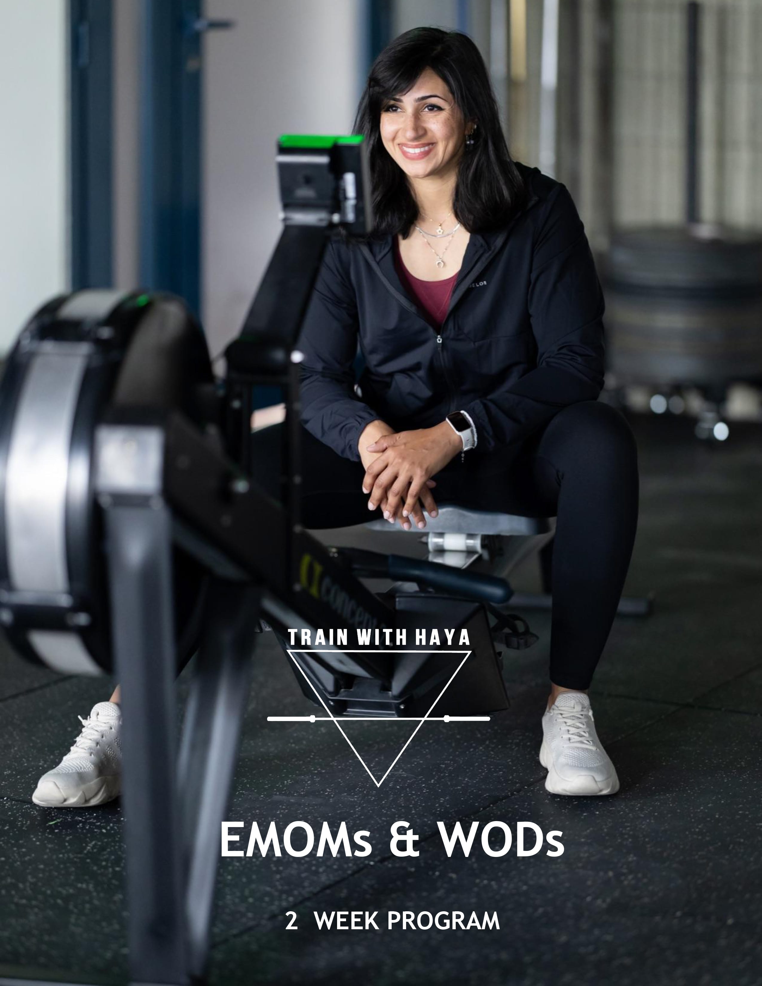A woman with long dark hair uses a rowing machine in the gym, smiling at the camera. She wears black workout gear and white sneakers. Text reads: "Train with Haya: EMOMs & WODs – 2 Week Program.