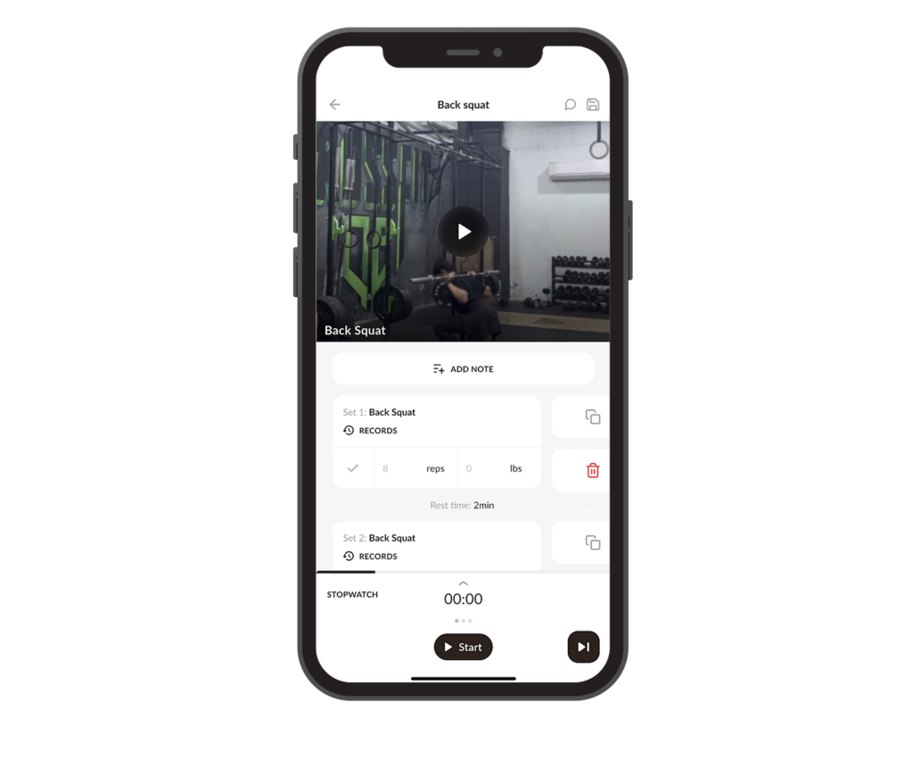 A smartphone displays a workout app with a video for “Back Squat.” Below the video are fields for adding notes, recording sets, reps, and weights. Stopwatch and start/stop buttons are at the bottom of the screen. Gym equipment is visible in the background video.